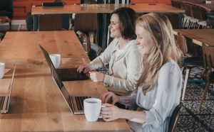 two women sitting in front of their laptops